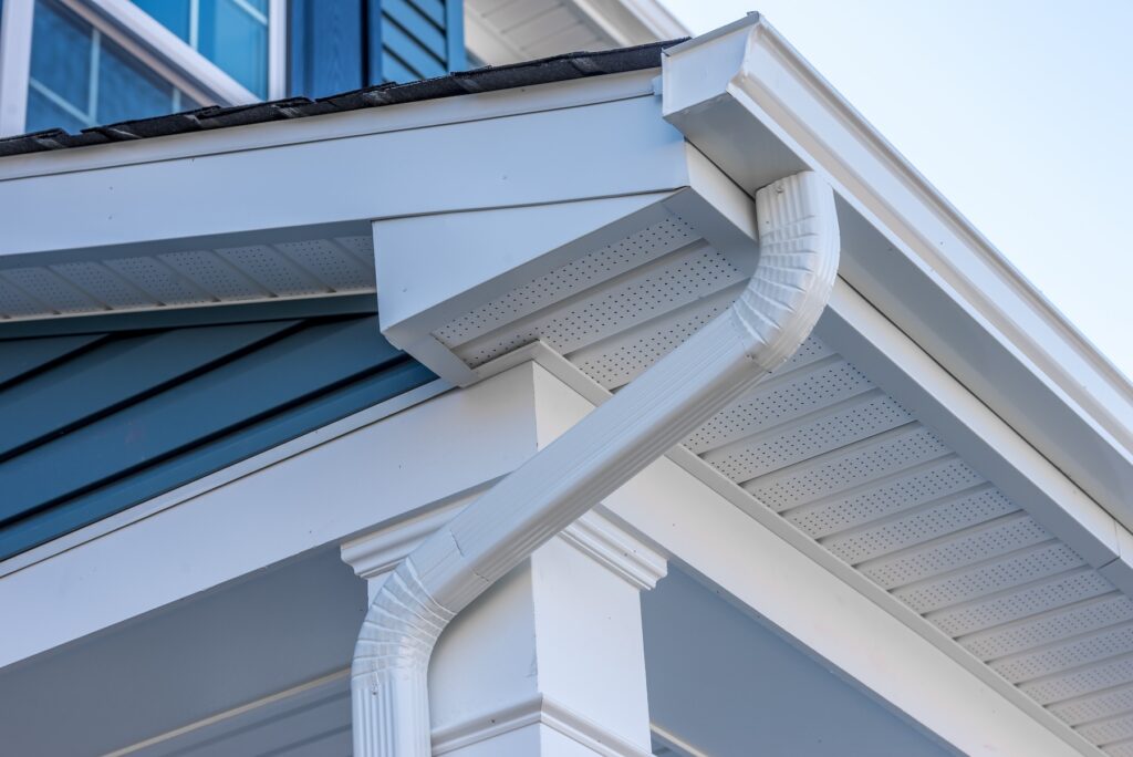 Close-up view of a white rain gutter and downspout installed by a gutter repair company in New Orleans.