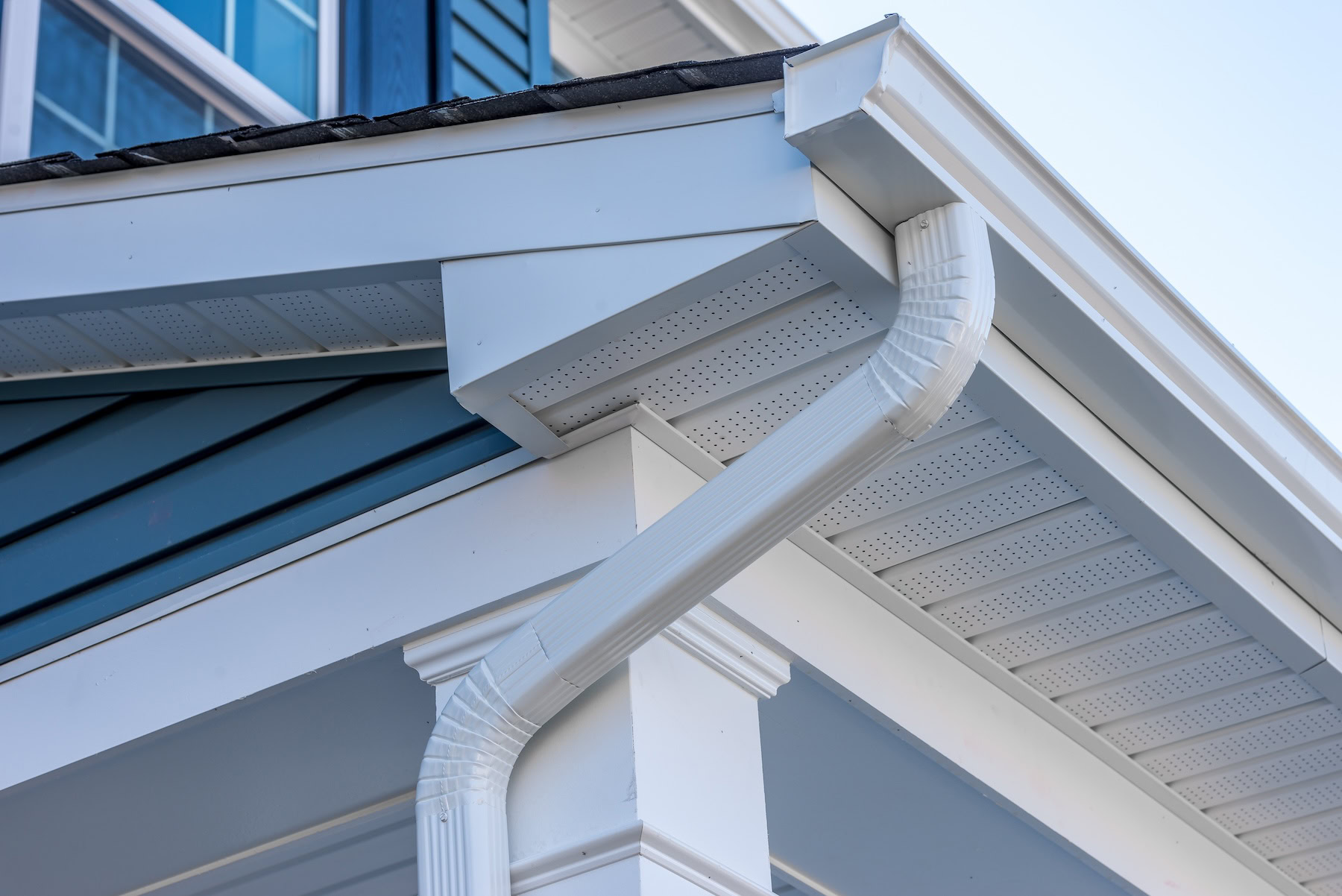 Close-up view of a white rain gutter and downspout installed by a gutter repair company in New Orleans.