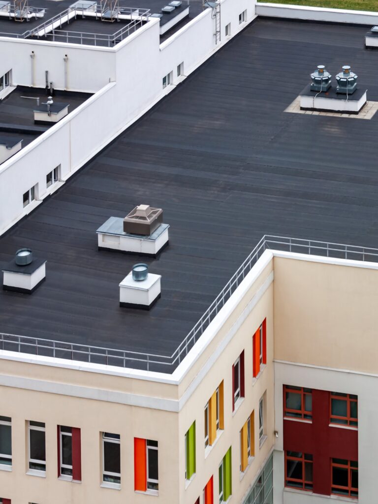 A modern flat-roofed building with rooftop vents and colorful window frames—contact us for a free roofing estimate in Biloxi.
