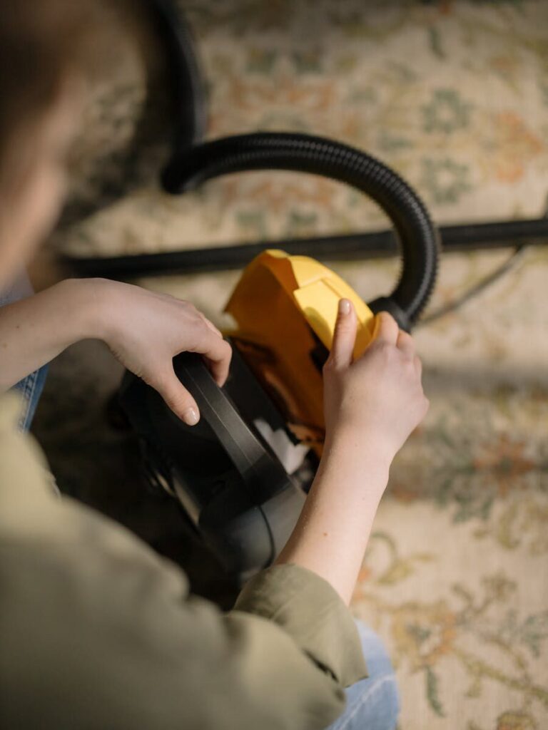 A cozy indoor shot featuring hands handling a vacuum cleaner, emphasizing cleanliness and home care.